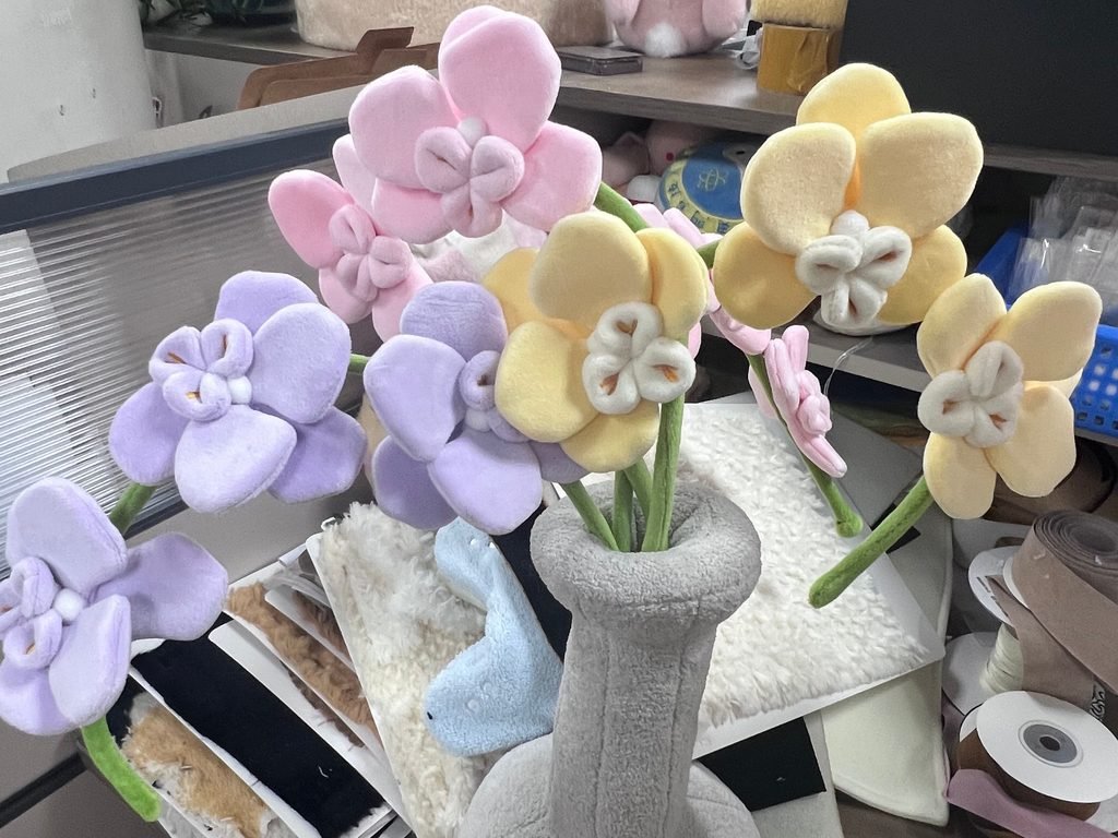 Single stem custom plush orchid flowers in pastel colors arranged in a plush vase for flexible retail display